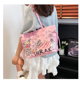 Detail of pink graffiti tote bag with cute cartoon prints on model's shoulder