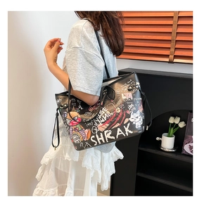 Close-up of black graffiti tote bag with colorful cartoon patterns and leather handles