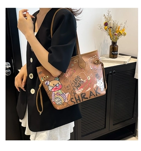 Detail of a brown tote bag featuring street-style graffiti and teddy bear patches