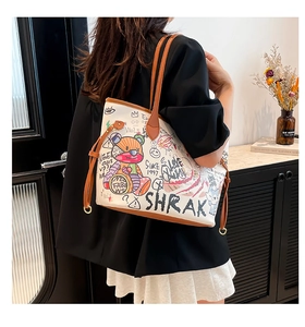Detail view of white tote bag with colorful graffiti bear patterns and leather handles