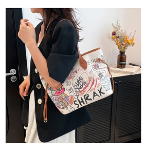 Detail view of large graffiti tote bag featuring cartoon prints and brown leather straps