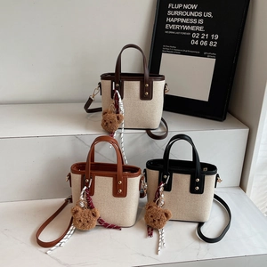 Trois mini sacs cabas en marron et noir avec breloques d'ours sur marches en marbre