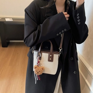 Sac seau en toile minimaliste avec garniture en cuir marron et breloque ours sur modèle