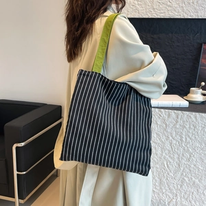 Minimalist black and white striped canvas tote bag with vibrant green shoulder straps