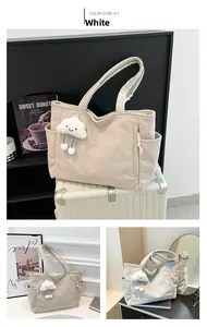 Detail of off-white corduroy tote bag featuring side zipper pocket and cloud smiley charm
