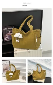 Detail of yellow corduroy tote bag with side pocket and cloud plush charm decoration