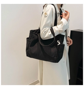 Detail of black corduroy tote bag showing side pocket and white rope decorative elements