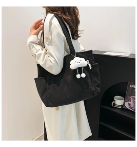 Close-up of black corduroy tote bag featuring a cute white cloud plush pendant and side pocket