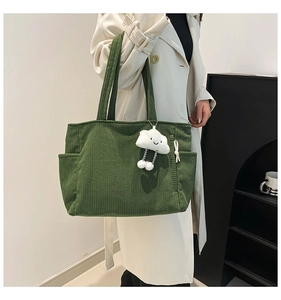 Detail of green corduroy tote bag with side pockets and a cute cloud plush pendant