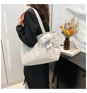 Detail of off-white corduroy tote bag featuring side pockets and a plush cloud charm