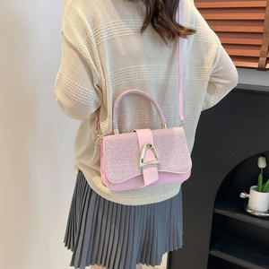Pink glitter crossbody flap bag with gold triangle buckle shown from a side view on a model