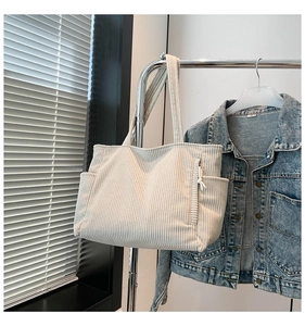 Close-up of cream corduroy tote bag showing ribbed texture and side pocket detail