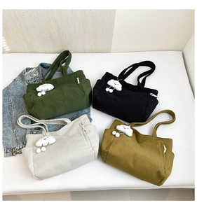 Detail of corduroy tote bags with plush cloud charms and functional side zipper pocket