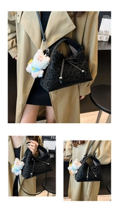 Detail of leopard print handbag with a bow and plush animal charm on leather strap