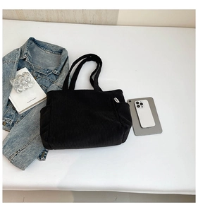 Detailed top view of a black corduroy tote bag with side pocket and daily essentials