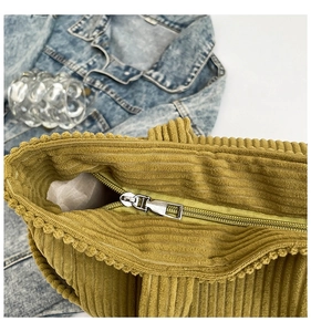 Detail of corduroy tote bag featuring metal zipper closure and textured vertical stripes
