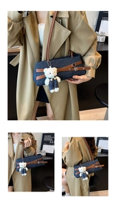 Detail of denim baguette bag with brown leather straps and cute plush bear charm