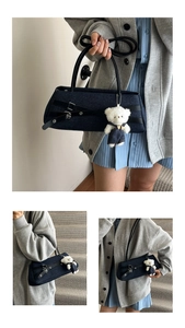 Detail of dark blue denim baguette bag featuring decorative strap and plush bear charm