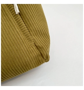 Detailed macro view of olive green corduroy fabric texture and stitching on tote bag