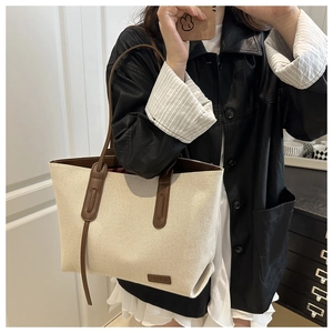 Dettaglio della borsa tote in tela con manici in pelle marrone ed etichetta moda interna