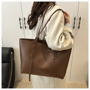 Close-up of a large brown PU leather tote bag with FASHION embossed logo and slim straps