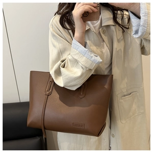 Dettaglio della borsa tote marrone in pelle con logo FASHION inciso e sottile tracolla