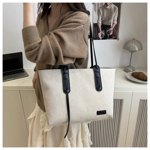 Grande borsa tote in tela con manici in pelle nera ed etichetta moda in un ufficio domestico