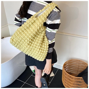 Detail of a large cream yellow popcorn textured tote bag worn on the shoulder