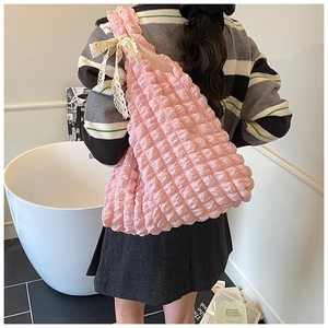 Detail of pink popcorn fabric shoulder bag featuring delicate lace bow and textured pleats