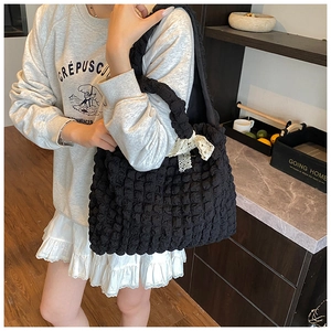 Detail of black bubble nylon tote bag with white lace bow and pleated texture finish