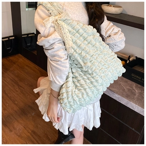 Detail of mint green popcorn textured tote bag featuring elegant lace bow straps