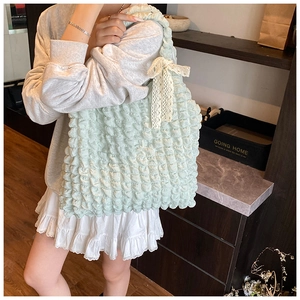 Detailed view of mint green puff textured tote bag with white lace bow decoration