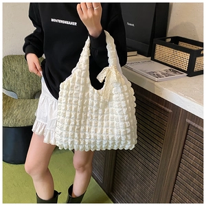 Detail of white bubble texture fabric with an elegant lace bow on a large shoulder bag