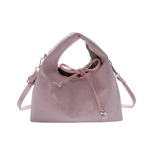 Pink faux leather handbag with drawstring pleats and metal bead accents on white background