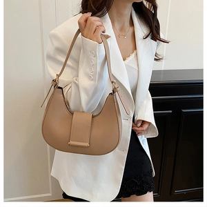 Close-up of khaki crescent underarm bag with adjustable buckle strap on model
