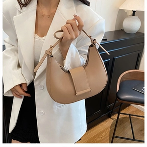 Detailed view of beige hobo bag featuring wide leather buckle and gold hardware