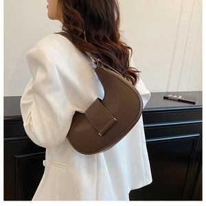 Detail of dark brown crescent shoulder bag with leather texture and golden metal buckle