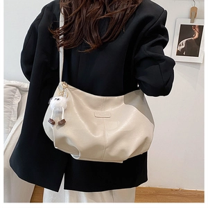 Détail du sac à main blanc crème en similicuir avec fronces et pendentif en peluche