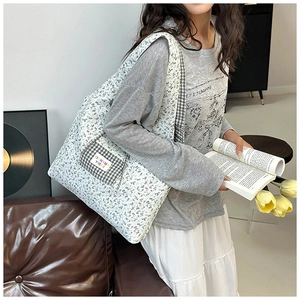 Detail of floral tote bag with a checkered side pocket shown in a cozy indoor setting