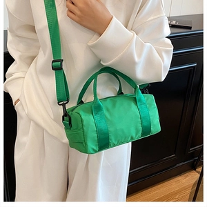Borsa boston in nylon verde con tracolla indossata da una modella in scena casual
