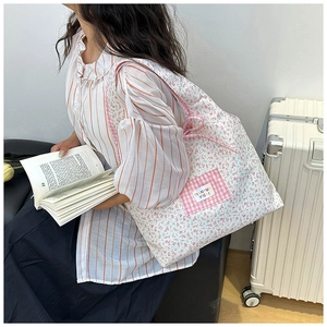 Close-up of floral canvas tote bag with pink plaid pocket and woven brand label
