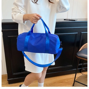 Dettaglio della borsa fitness blu cilindrica in nylon con tracolla e manici robusti