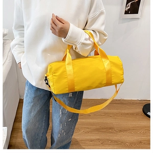 Primo piano di un borsone giallo brillante in nylon con tracolla e manici per trasporto