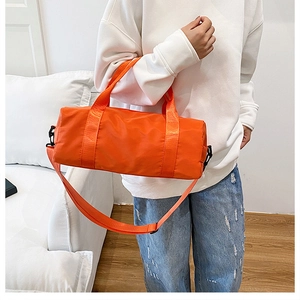 Close-up of bright orange cylindrical gym bag with water-resistant nylon texture