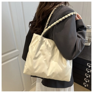 Detail of cream tote bag with diamond texture and woven handle on shoulder