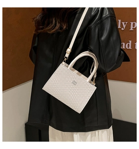 Close-up of woven texture white leather crossbody bag with silver metallic logo detail