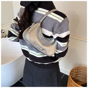 Detail view of the silver metallic leather underarm bag with a smooth crescent shape