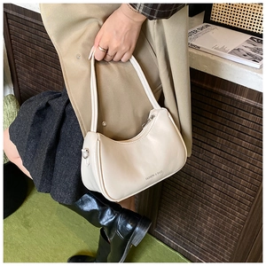 Detail of cream minimalist crescent shoulder bag with silver hardware and logo text
