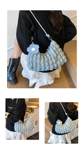 Détail du sac croissant plissé bleu clair avec pendentif fleur et anneaux dorés