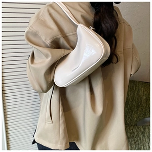 Detail shot of a minimalist cream-colored underarm bag featuring subtle wrinkled leather texture